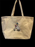 Embroidered canvas tote bag depicting two cartoon geese, one wearing a blue bonnet and the other holding a small pink cake adorned with purple flowers